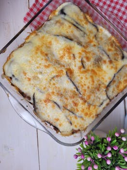 Top view of a golden baked cheese and eggplant casserole in a glass dish.
