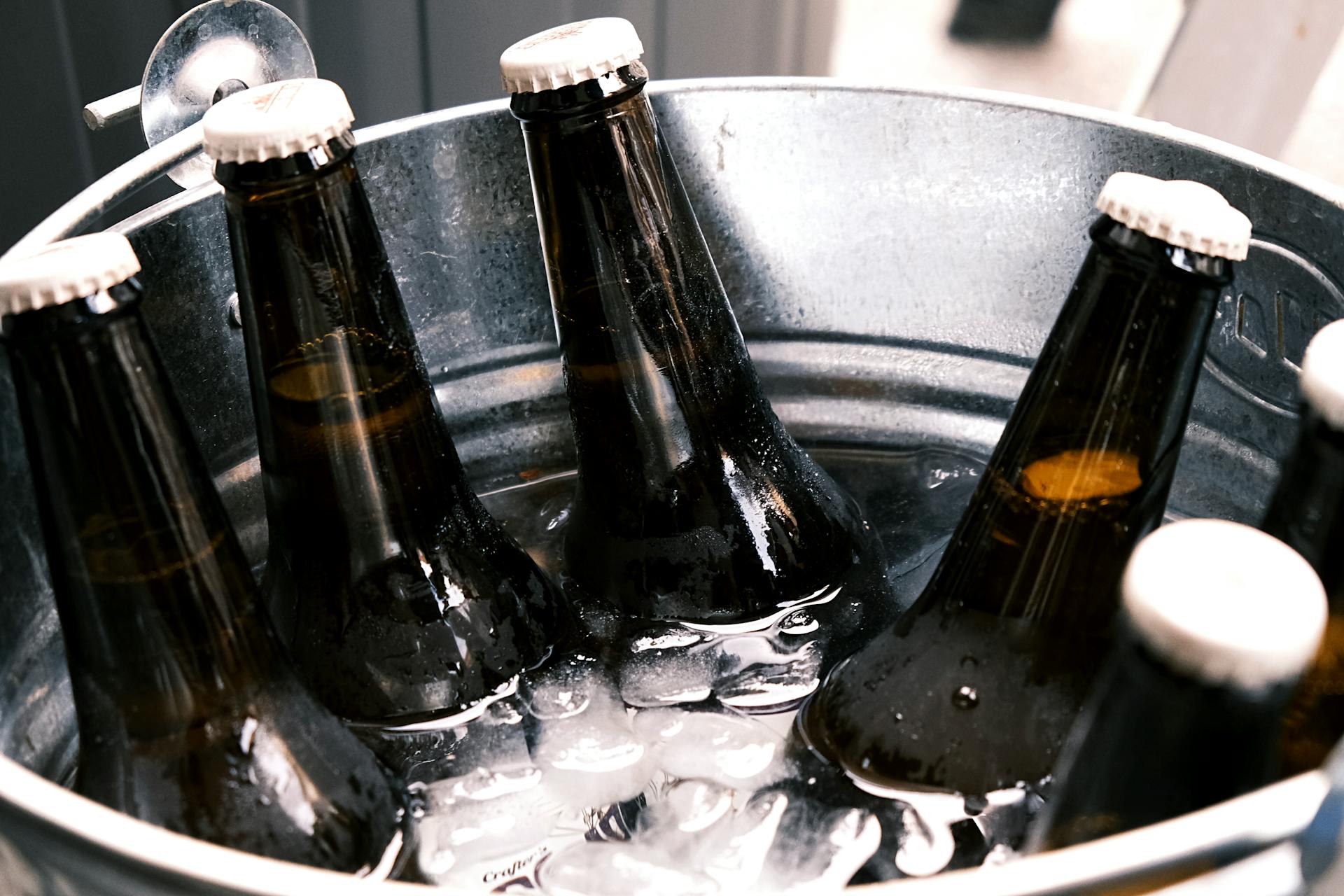 Refreshing ice-cold beer bottles in a metal bucket, perfect for party vibes.