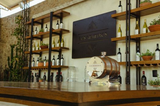 An elegant wine bar interior featuring a decorative barrel and neatly arranged wine bottles on shelves.