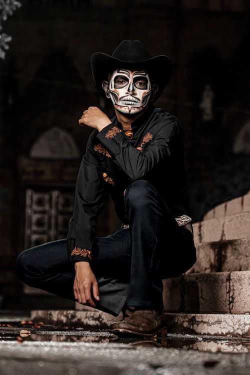 Free Man posing in traditional skeleton makeup, embracing cultural fashion in an urban setting. Stock Photo