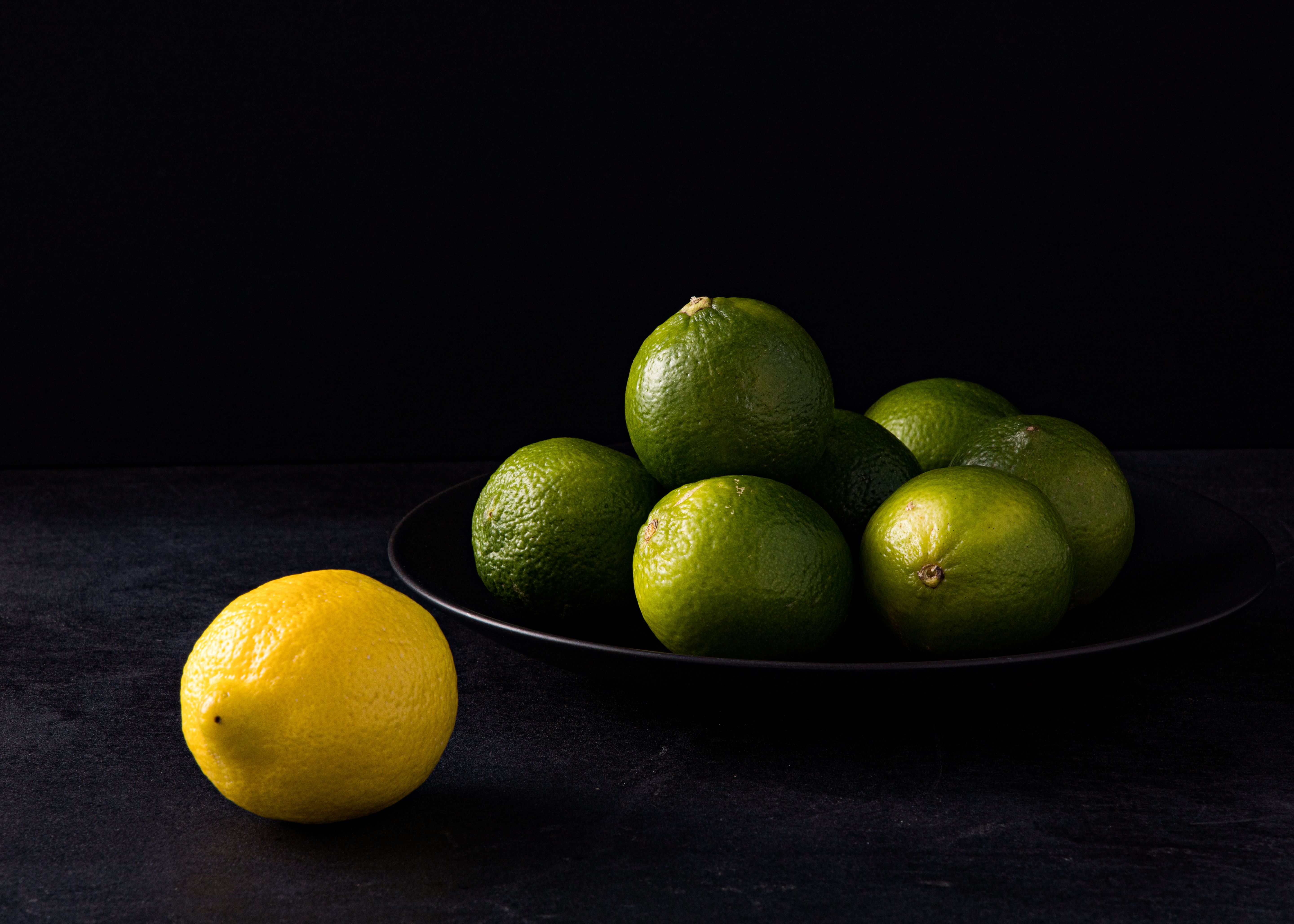 Single Lemon and Pile of Limes on Plate · Free Stock Photo