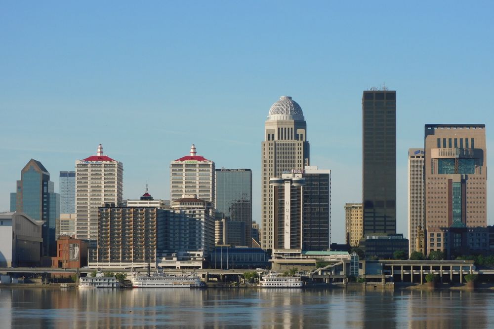 Stunning view of Louisville's skyline with modern skyscrapers reflecting on river.