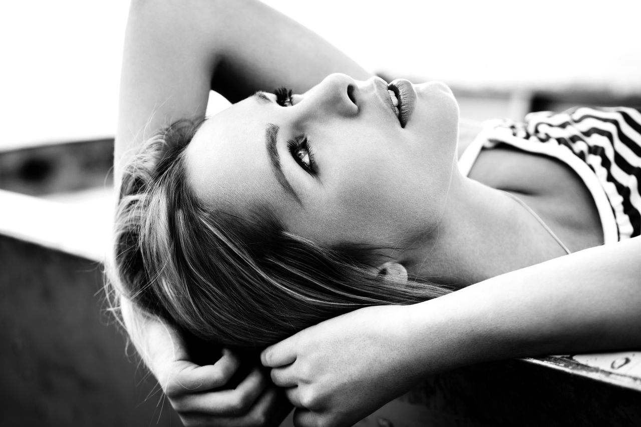 artistic black and white portrait of a woman lying down exuding elegan