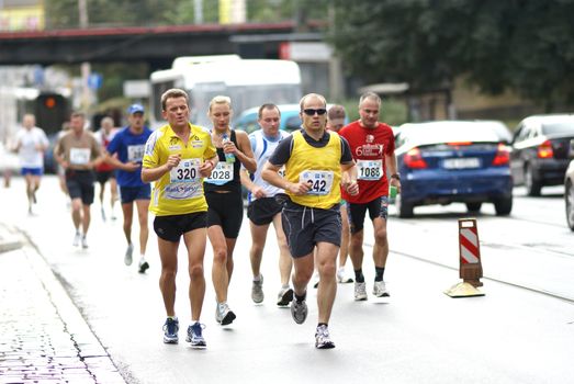 Group of diverse runners participating in a lively street marathon race, showcasing determination and teamwork.