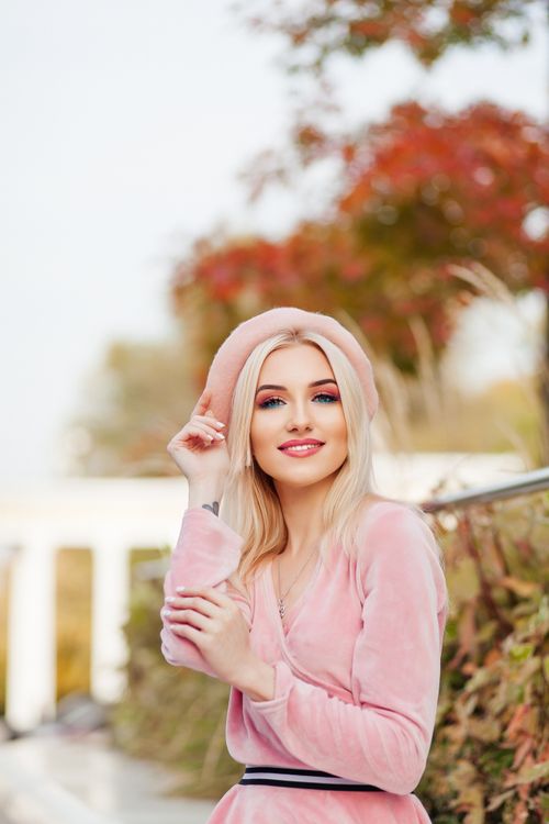 Free Stylish woman in pink posing outdoors with autumn leaves in the background. Stock Photo