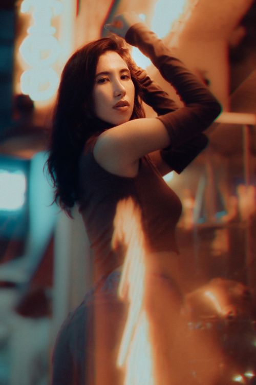 Free Elegant woman posing in a vibrant, illuminated night scene, exuding confidence and style. Stock Photo