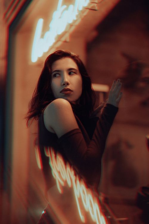 Free A fashionable woman poses near a neon-lit store window reflecting vibrant nightlife vibes in Fethiye, Türkiye. Stock Photo