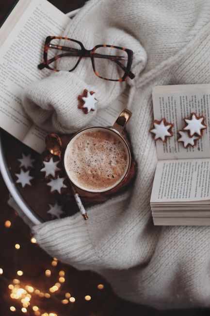 Warm and inviting photo of hot chocolate, open book, and cookies for a cozy winter vibe.
