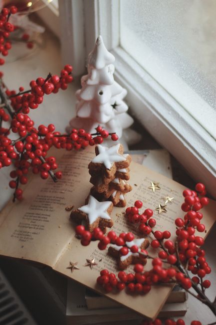 Festive Christmas setting with cookies, red berries, and decorations by a window.