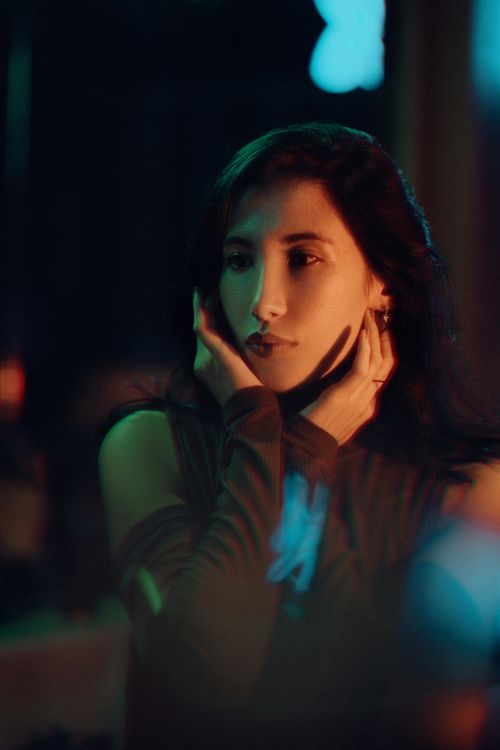 Free Portrait of a woman in soft, dramatic lighting with a thoughtful expression. Stock Photo