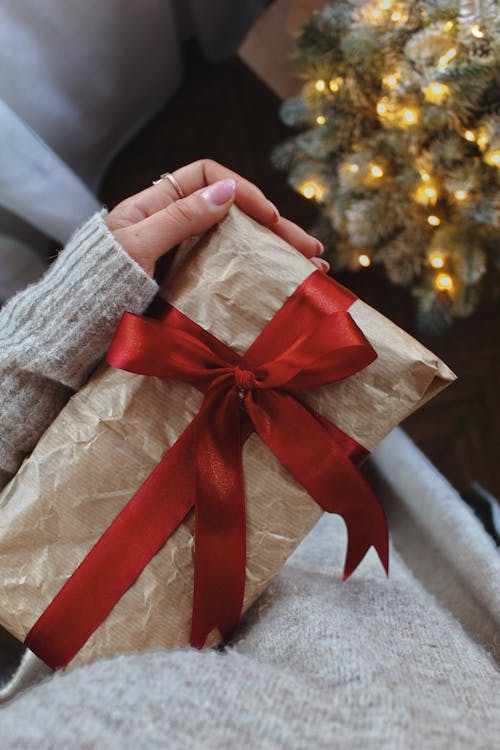 Woman Holding a Christmas Present Wrapped with Red Ribbon