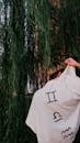 Back View of a Man Wearing Clothing with Zodiac Symbols, Standing under a Willow Tree