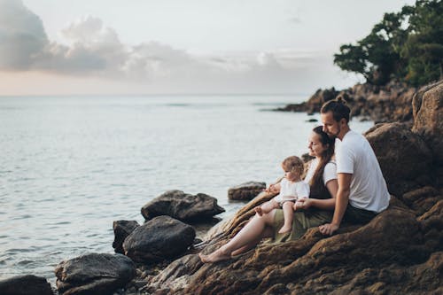 男人和女人坐在海边的岩石上