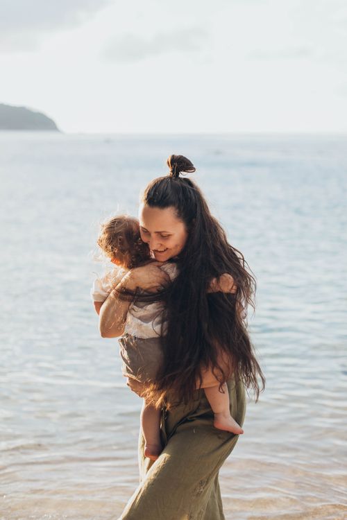 Free Heartwarming moment of a mother embracing her child at the beach on a sunny day. Stock Photo