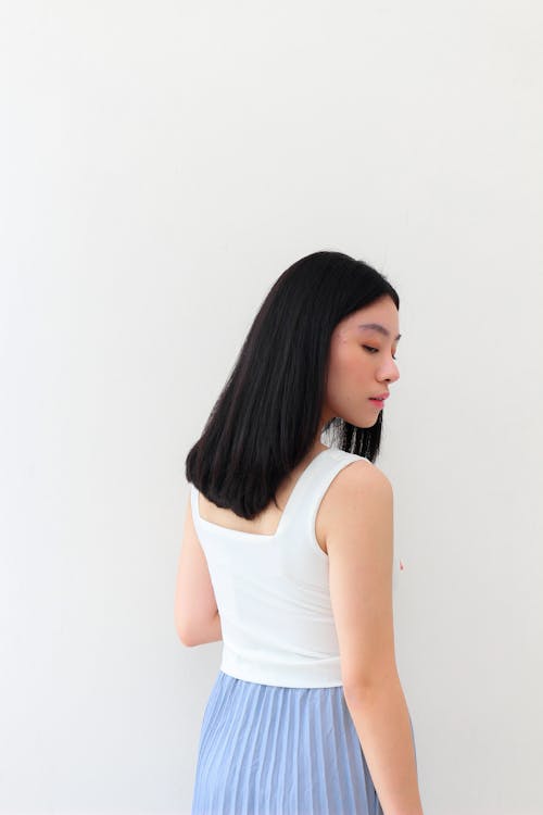 Young Woman in a Minimalistic Outfit Standing against a White Wall 