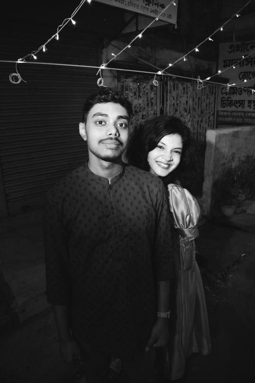 Free A joyful young couple standing together on city streets at night, captured in black and white. Stock Photo