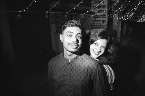 Free Black and white photo of a young couple smiling under city lights at night. Stock Photo