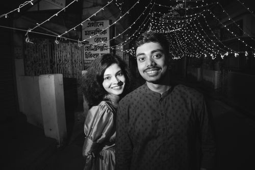 Free A happy couple posing together under string lights at night, smiling. Stock Photo
