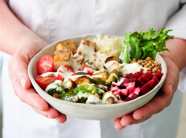 Grain bowl with roasted vegetables held in two hands, photo by Nadja M on Pexels