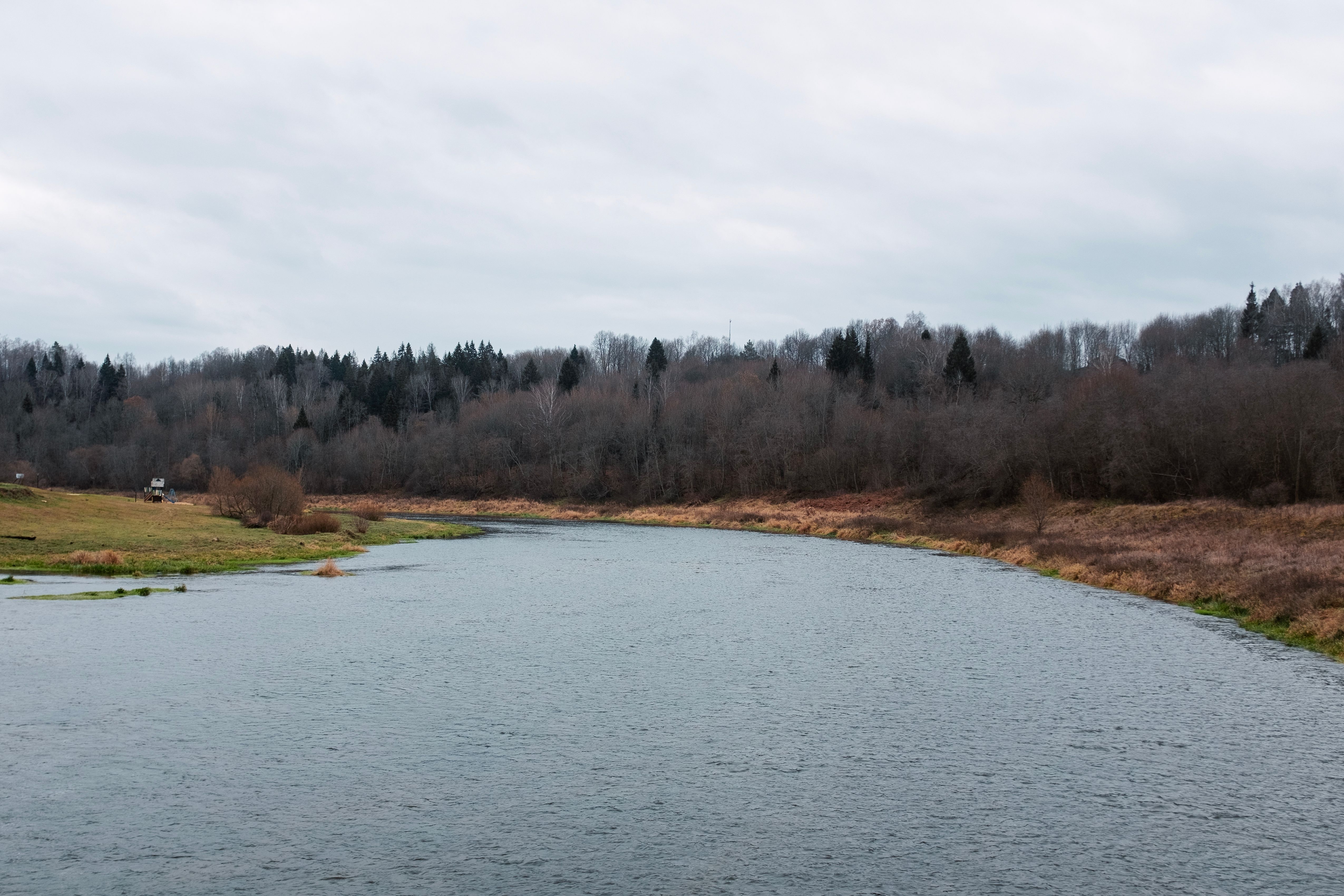 Tranquil river scene in Nesterovo, Russia showcasing autumnal trees and flowing water.