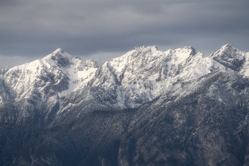 View of Snowcapped Mountains under a Cloudy Sky 