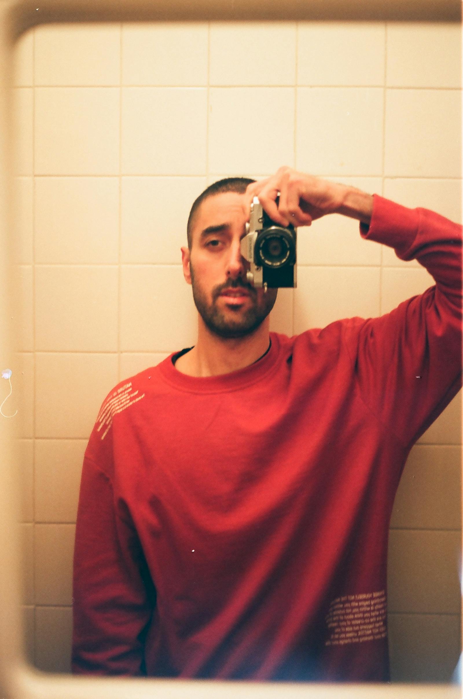 Direct-flash mirror portrait in a dim room with 90s disposable feel