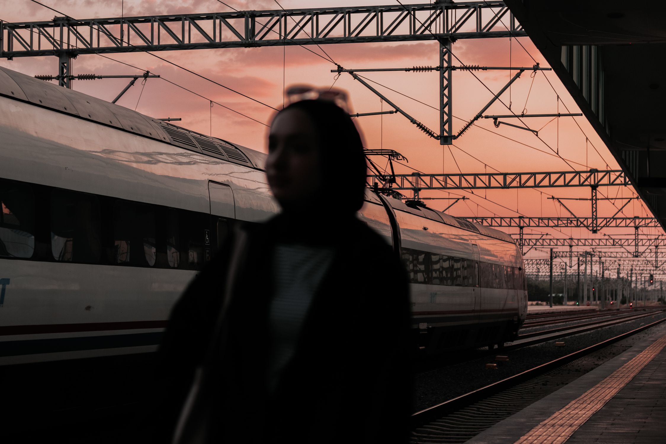 Solo woman traveler at a European train platform at sunset