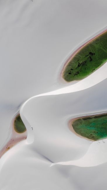 Stunning aerial photo showcasing white sand dunes and green lagoons in a desert landscape.