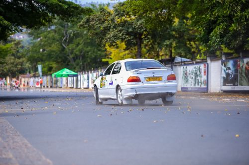 Free A white car performs a drift on an urban road, showcasing speed and skill. Stock Photo