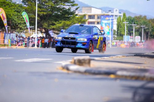 Free Blue sports car speeding during a daytime race on a city street, surrounded by cheering spectators. Stock Photo