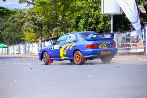 Free A blue rally car with graphics drifting on an open asphalt track during a daytime event. Stock Photo