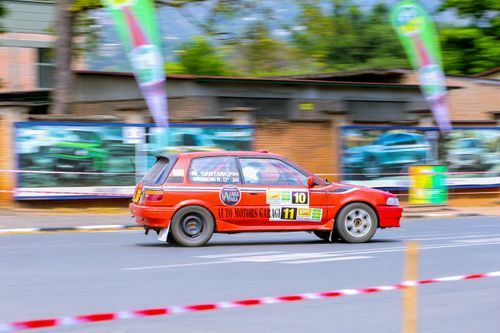Free A vibrant red hatchback speeds by during a street racing event, highlighting motion and competition. Stock Photo