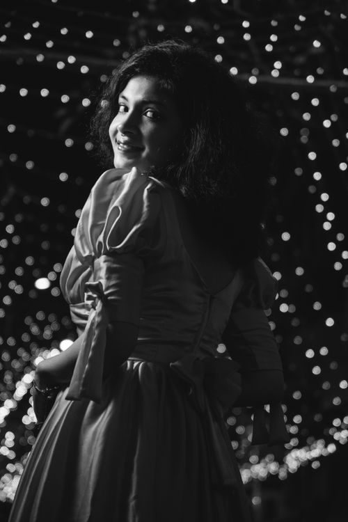 Free Back view of a woman in evening dress smiling with elegant bokeh background. Stock Photo