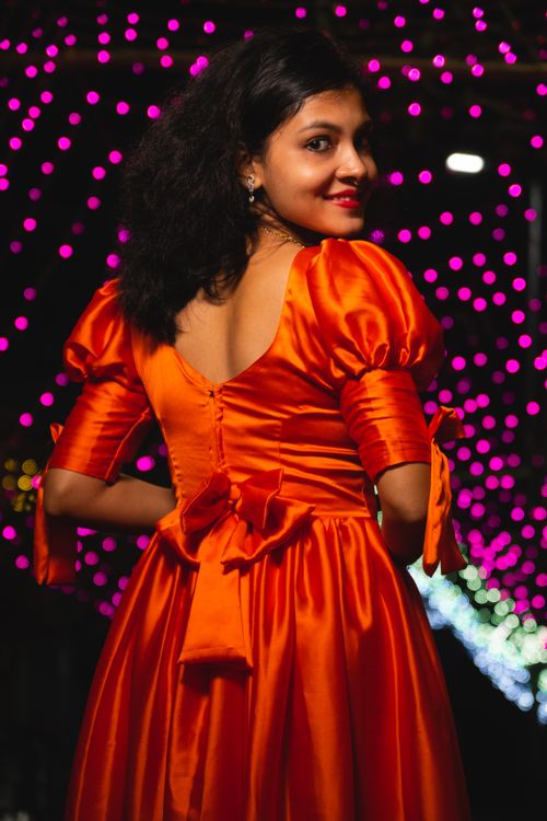 Free Elegant woman in a vibrant red dress poses outdoors under twinkling lights at night. Stock Photo