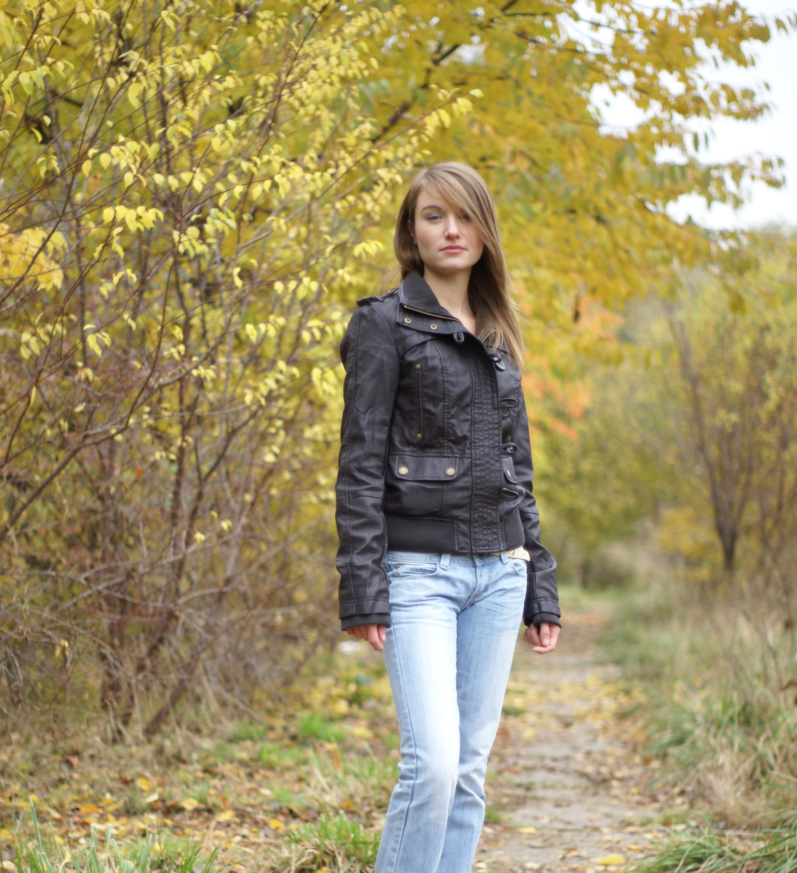 A woman in jeans and jacket standing on a path · Free Stock Photo