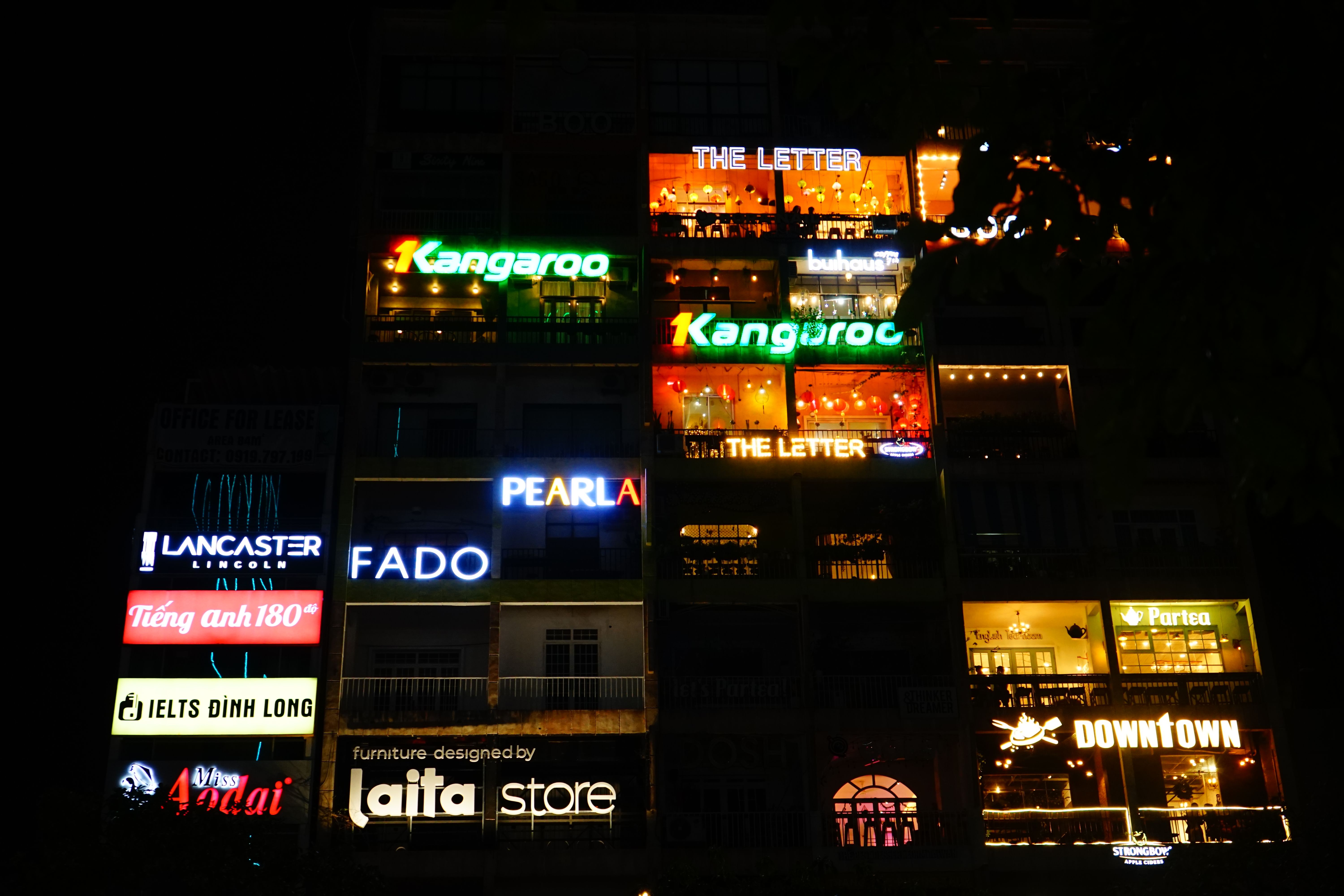 A vibrant night scene of a building facade with neon signs in Ho Chi Minh City, Vietnam.