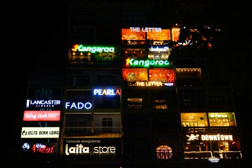 Free A vibrant night scene of a building facade with neon signs in Ho Chi Minh City, Vietnam. Stock Photo