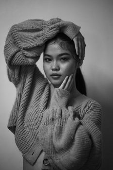 Monochrome portrait of woman in knitted sweater, posing artistically.