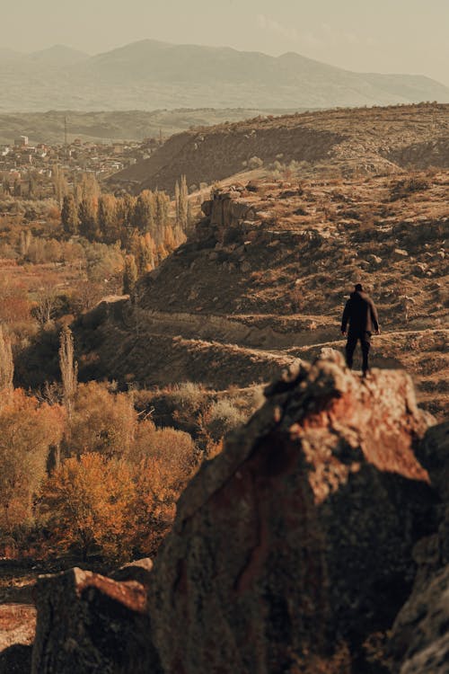 A man standing on top of a rock overlooking a valley