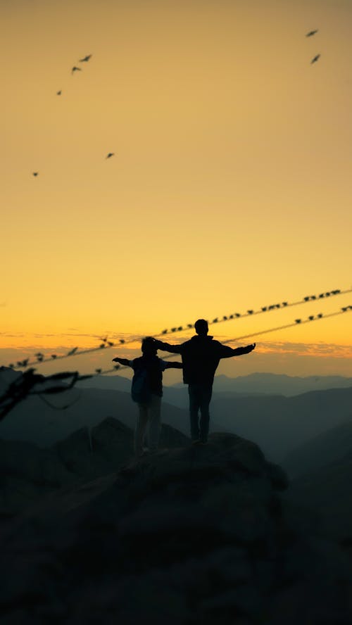 two men's standing on the top of hill under the foggy sky 