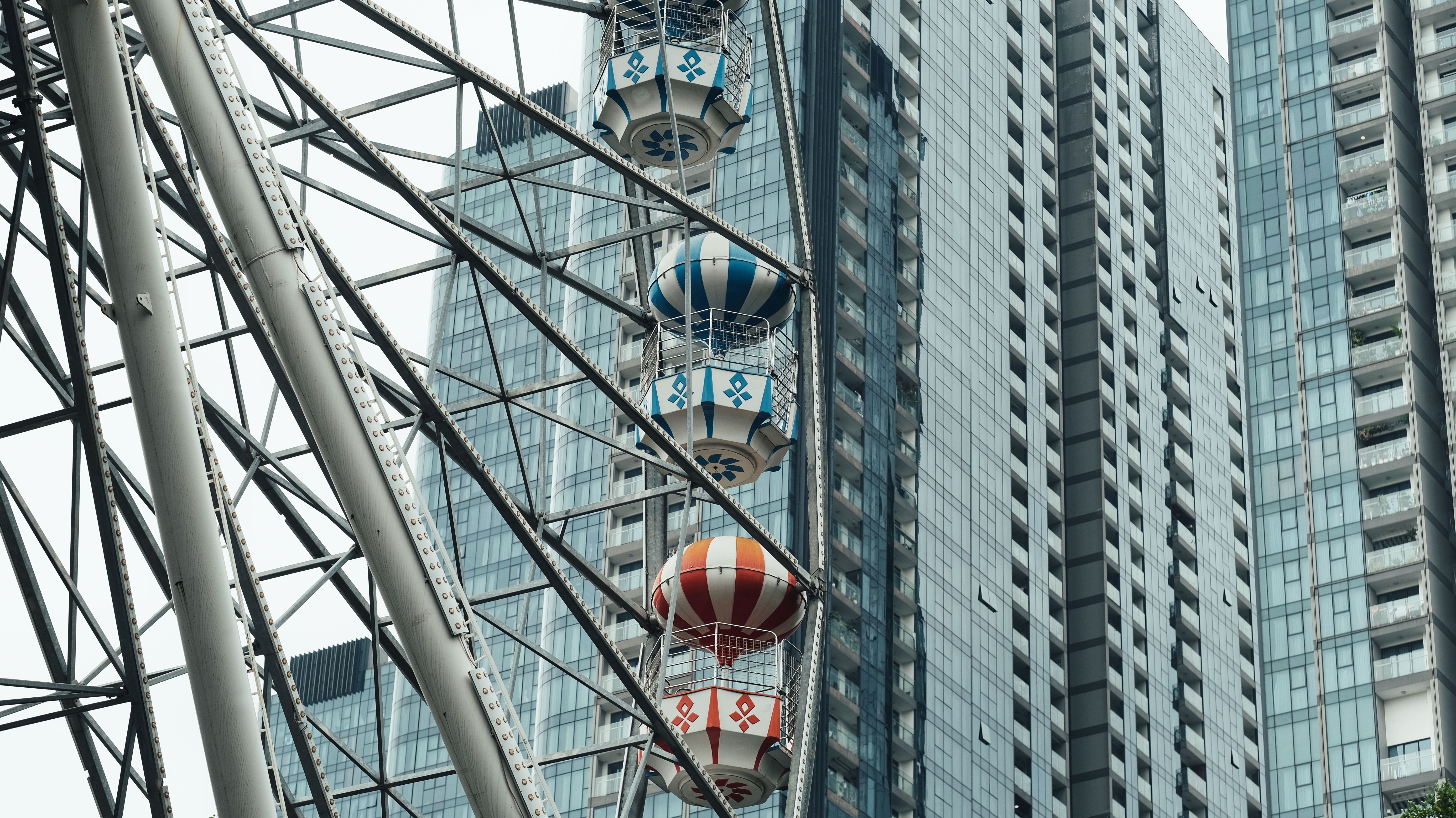 Ferris wheel against modern glass skyscrapers in urban setting.