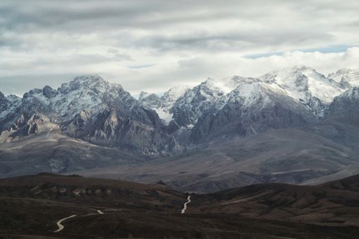 Breathtaking view of snowcapped mountains and winding path through a tranquil valley.