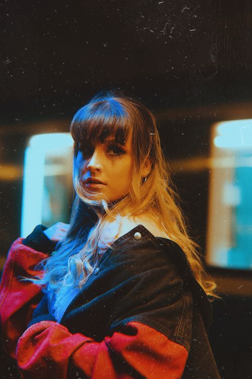 Free Portrait of a woman in vintage urban lighting, exuding a retro fashion vibe. Stock Photo