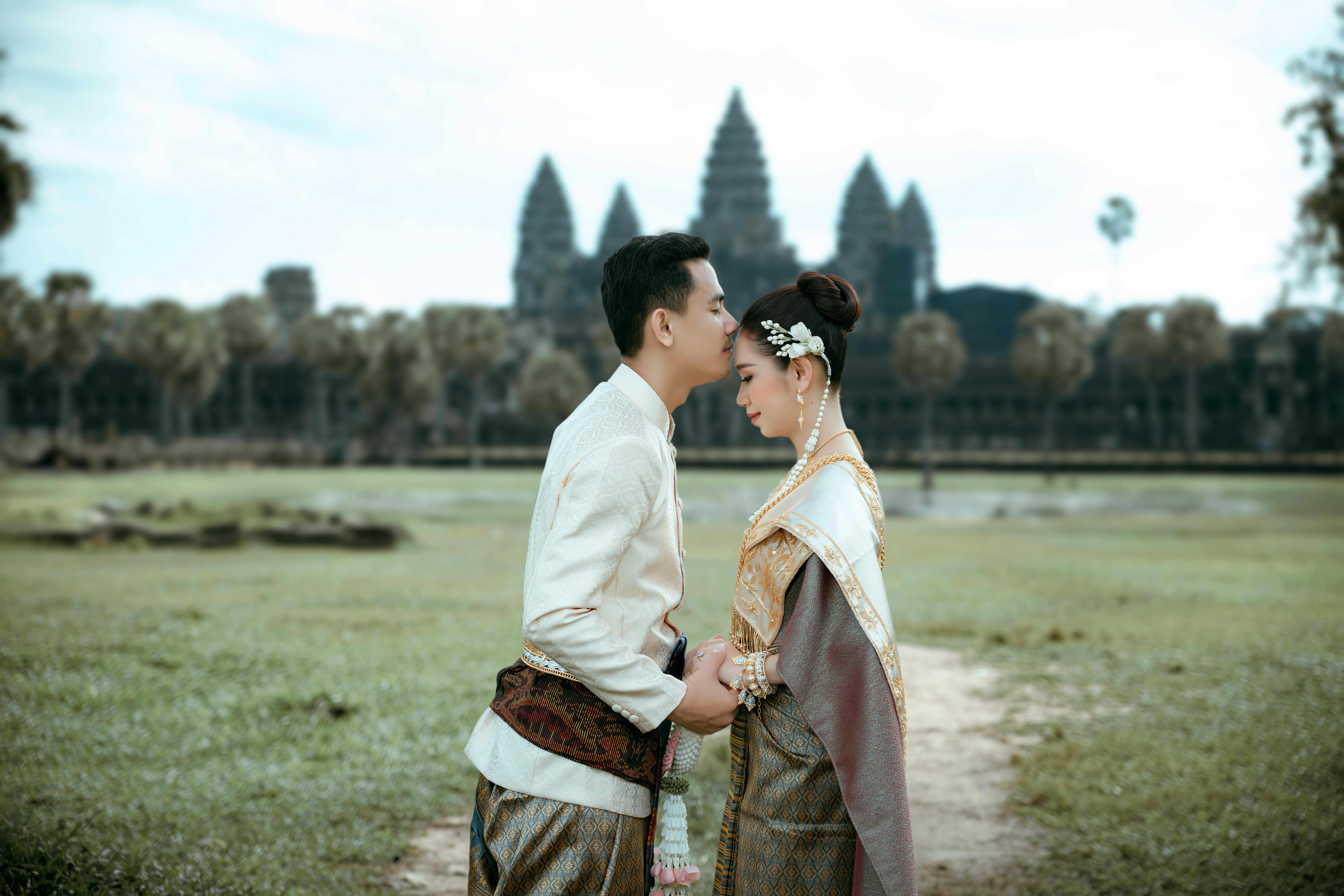 a couple in traditional clothing standing in front of a temple