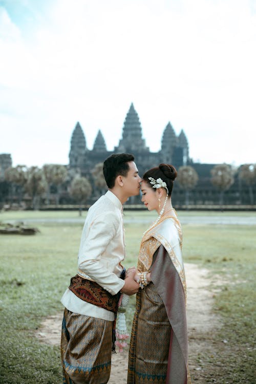 A couple in traditional clothing standing in front of a temple