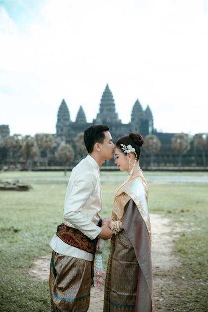 A couple in traditional clothing standing in front of a temple · Free Stock  Photo