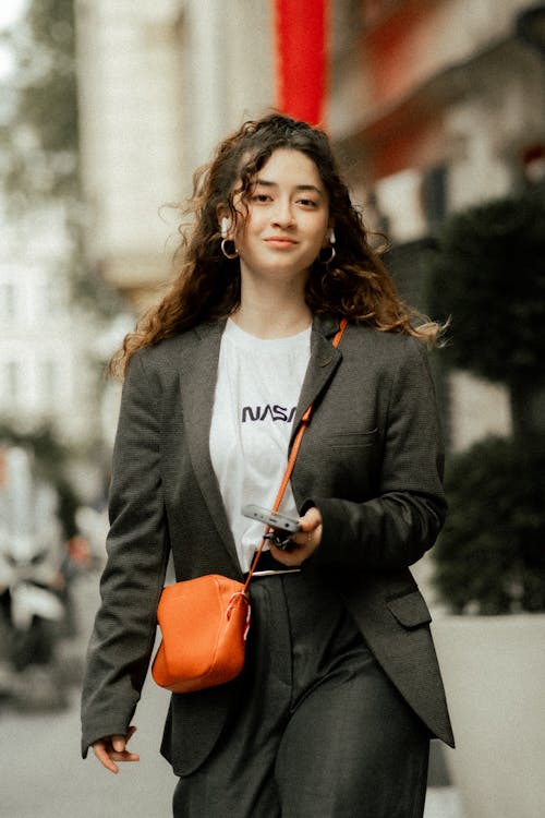 Smiling Woman Wearing Orange Bag Walking down Street