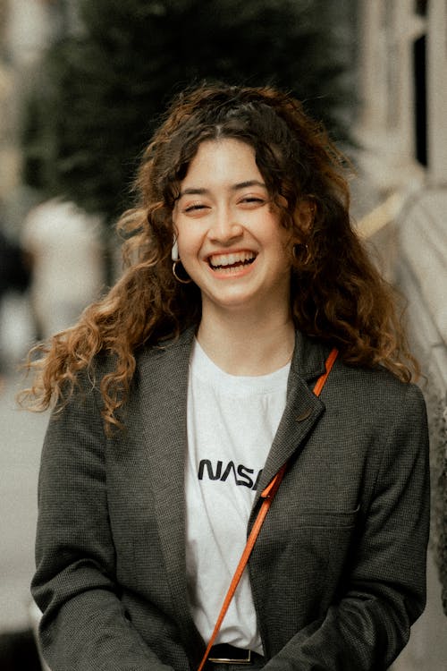 Young Woman with Curly Hair Posing in Gray Blazer and White T-Shirt