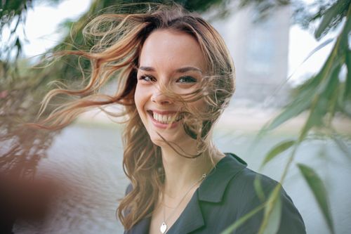 Free Portrait of a smiling woman with tousled hair outdoors in Berlin. Stock Photo