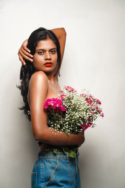 Free Elegant fashion portrait of a woman holding a vibrant floral bouquet against a neutral backdrop. Stock Photo
